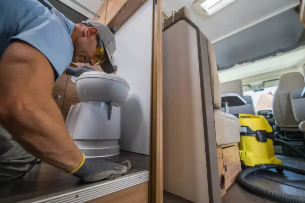 Caucasian Man Carefully Cleaning Each Surface of Motorhome Interior Elements Preparing it For a Long Storage Period. Professional Vacuum Cleaner in the Background. Recreational Vehicle Post Travel Care and Maintenance Theme.